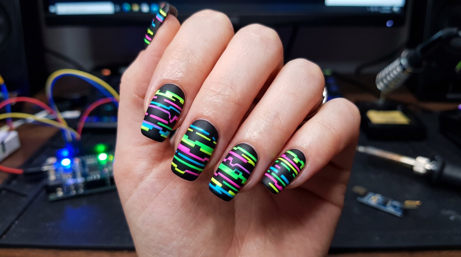 Close-up of nails styled with digital glitch stripe nail art featuring metallic silver lines and dark geometric accents.