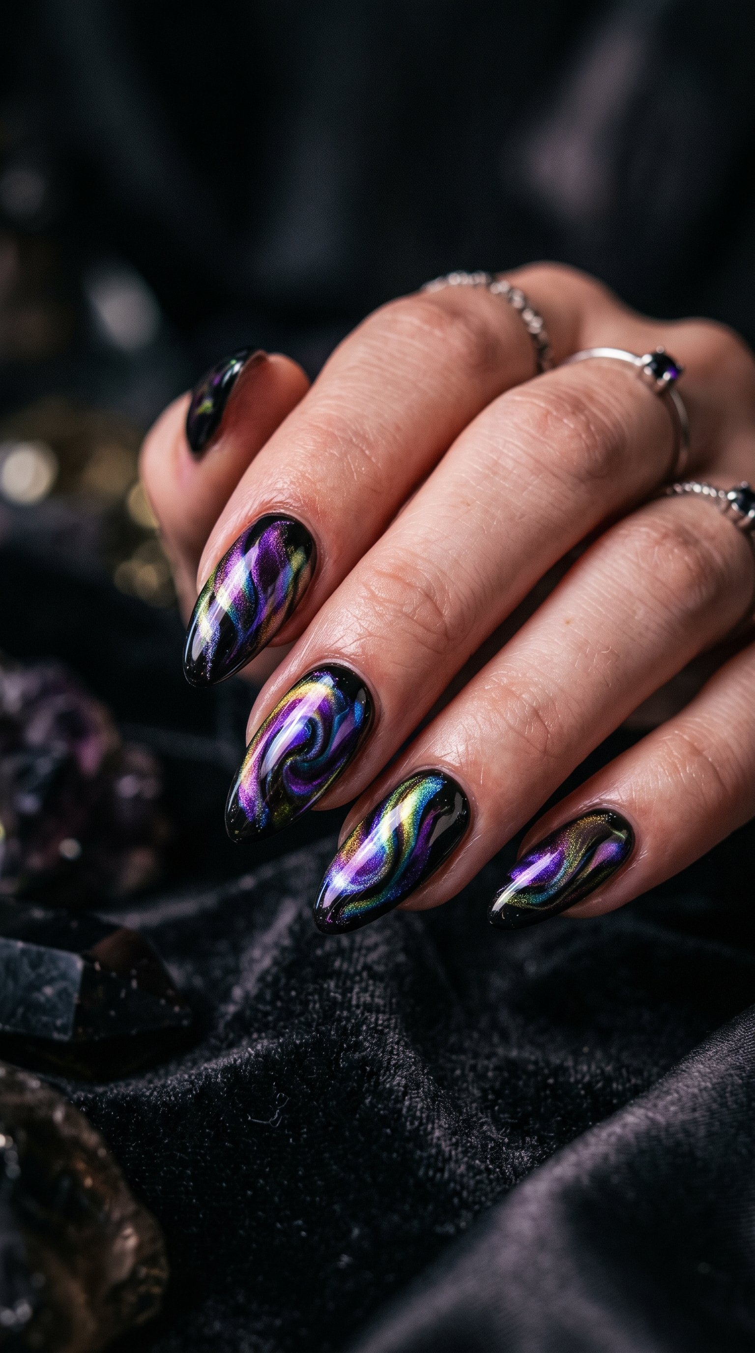 Metallic iridescent oil slick nail art showing chromatic shifts of purple, blue, and green on dark nails.