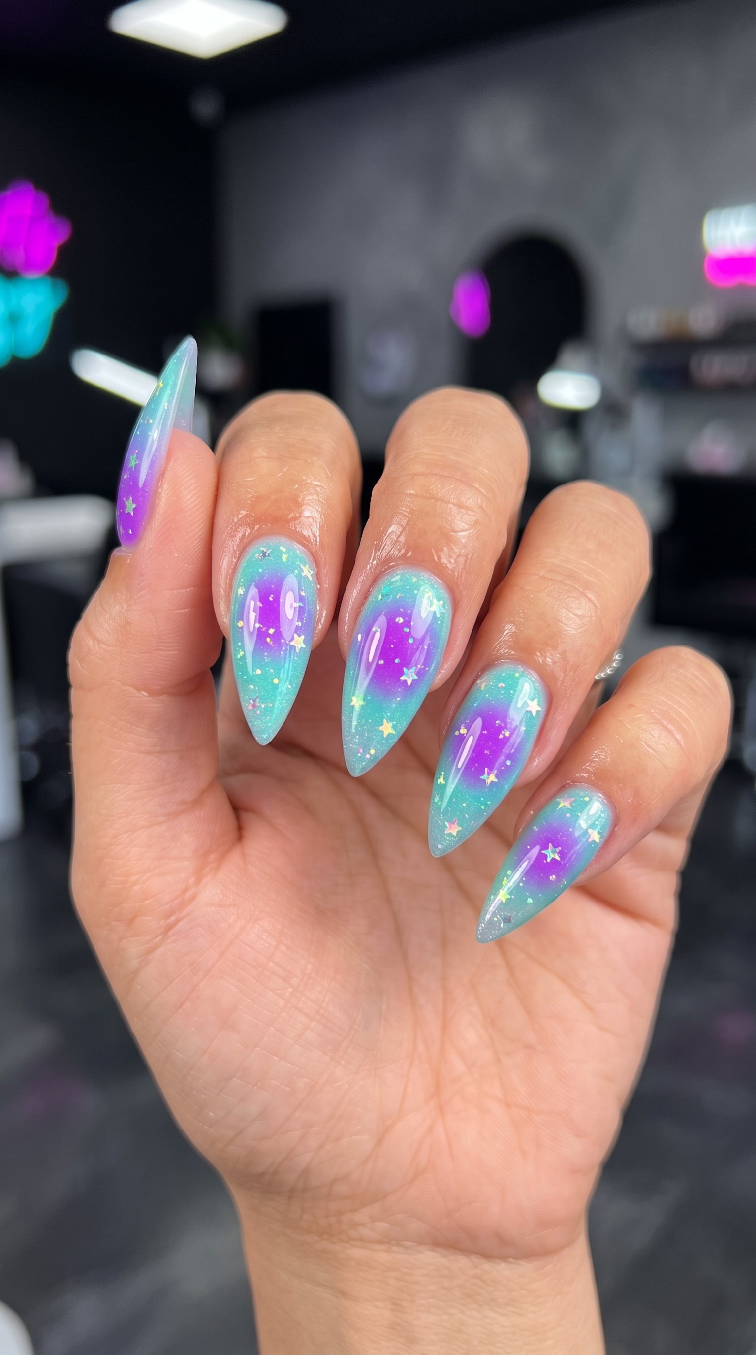 Stiletto acrylic nails with mint green and purple aura gradient art, fine glitter, and holographic star sequins