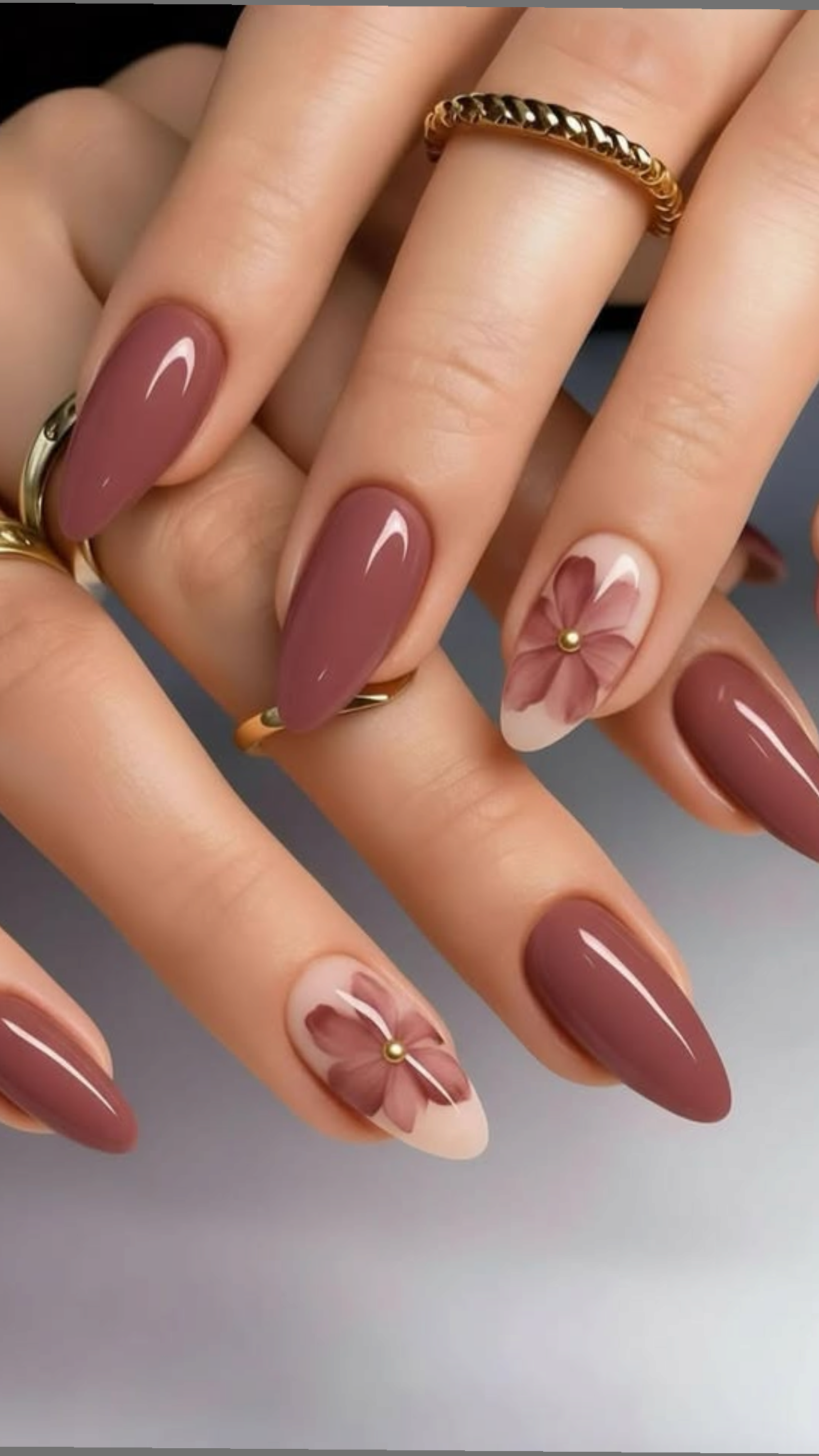 Glossy dusty rose almond-shaped nails with a sheer accent nail featuring a soft floral pattern and a gold stud center.