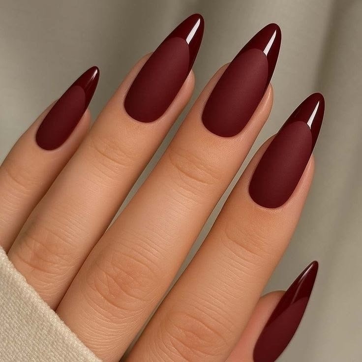 Long almond-shaped nails with a matte dark burgundy base and glossy maroon French tips