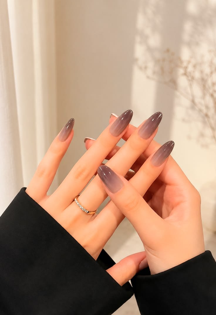 Close-up of elegant almond-shaped acrylic nails with a glossy brown ombre gradient design.